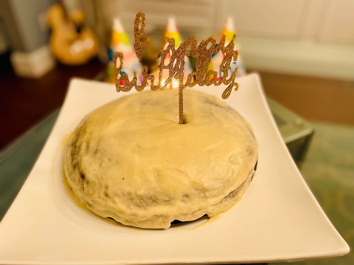 A frosted cake with a Happy Birthday topper