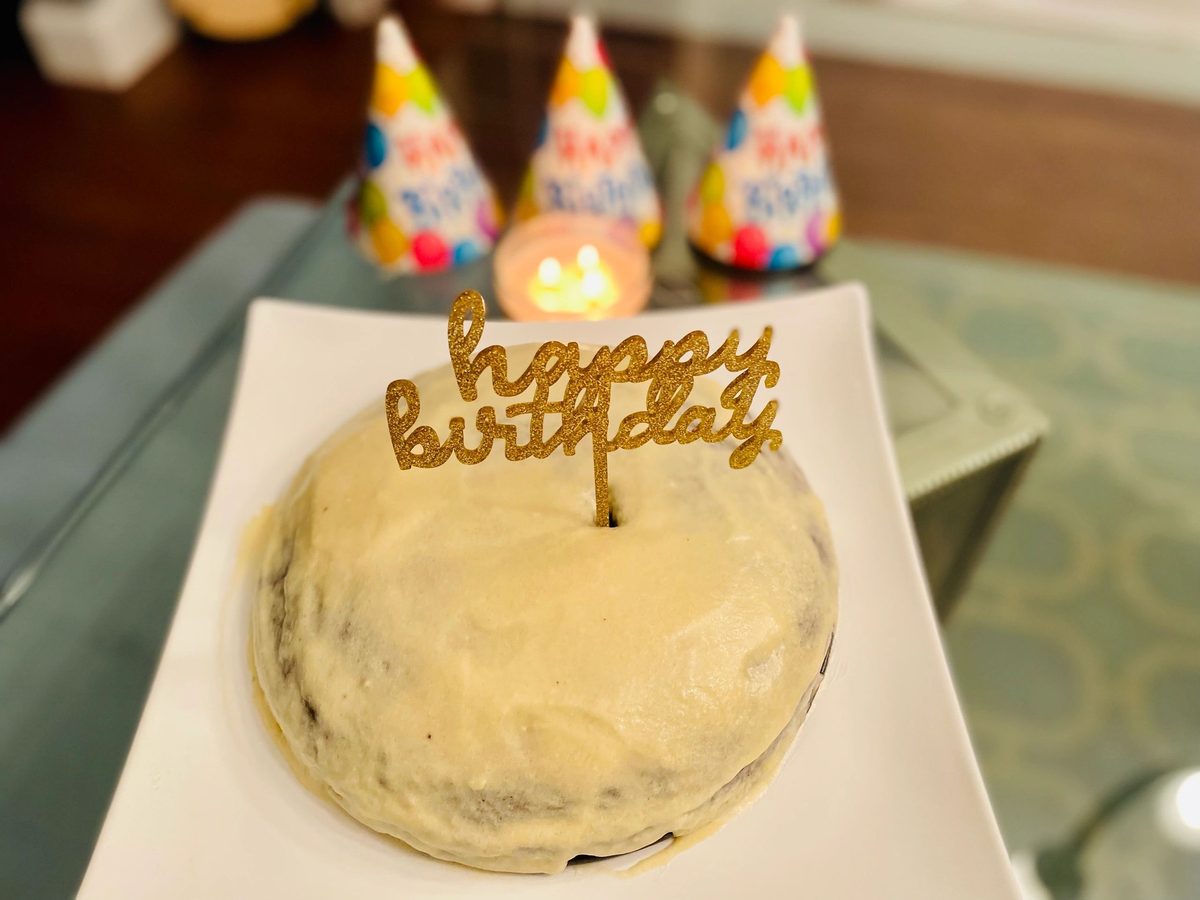 A frosted cake with a Happy Birthday topper and party hats