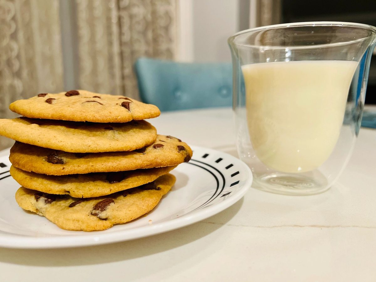 A stack of chocolate chip cookies with a glass of milk