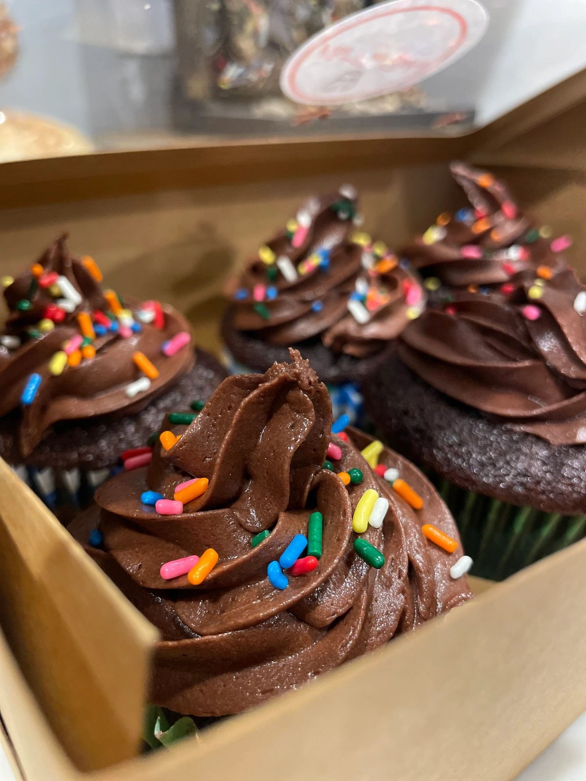 Chocolate cupcakes with chocolate frosting and sprinkles in a box