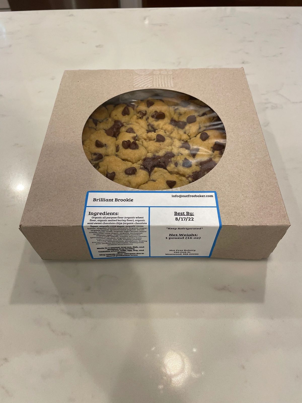 A cookie cake packed in a windowed box with its ingredient label