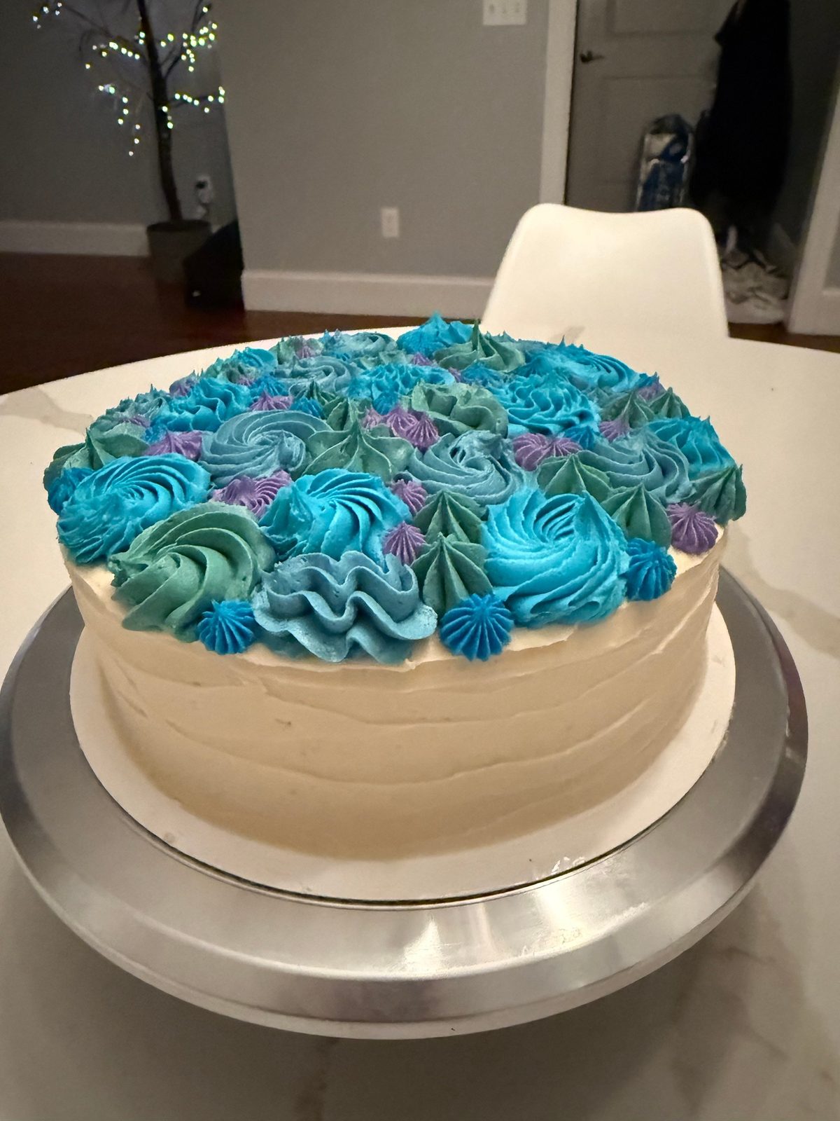 Layer cake topped with blue, green and purple buttercream rosettes