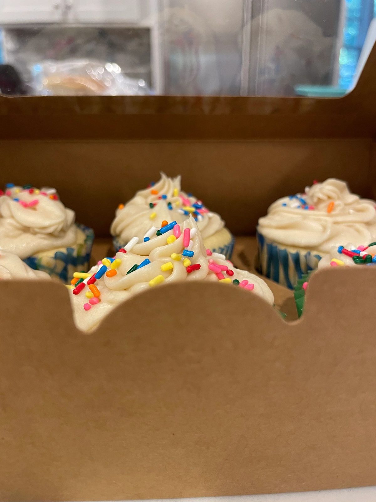Vanilla cupcakes with sprinkles in a bakery box